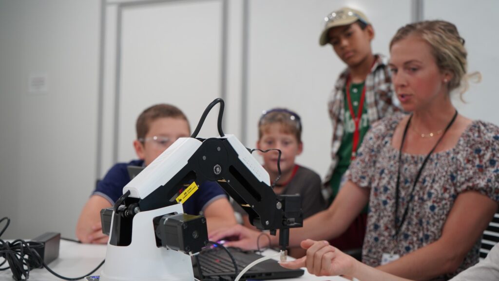 Students observe professional as she demonstrates robotic arm.