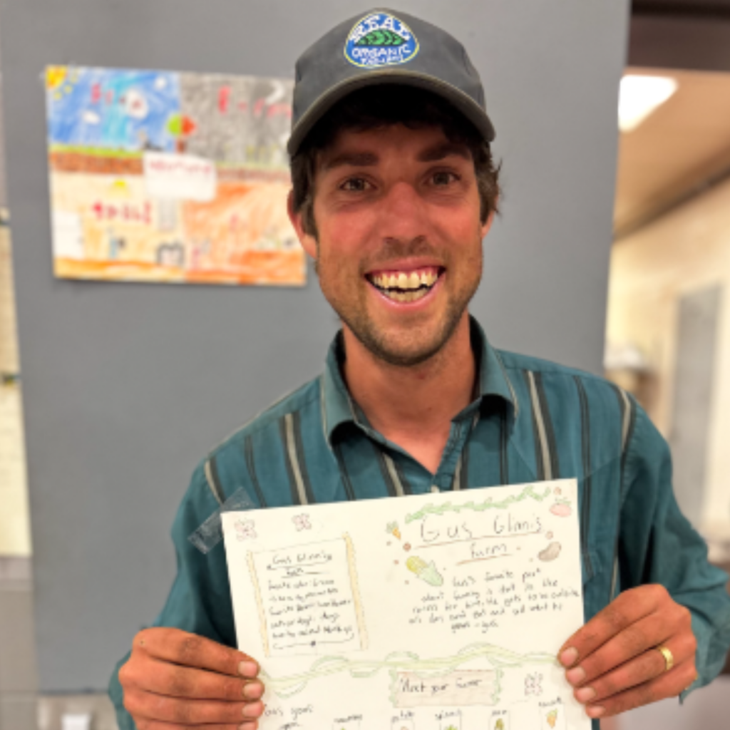 Gus Griffin poses with student poster made after visit to his farm Glinnis Hill farm in Northfield, VT